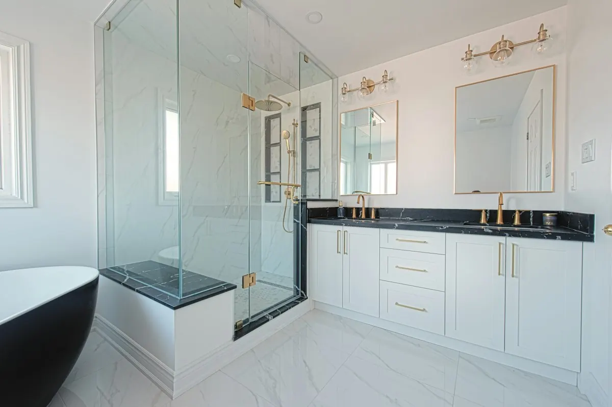 Remodeled bathroom with a frameless glass shower, a tiled bench and a double vanity