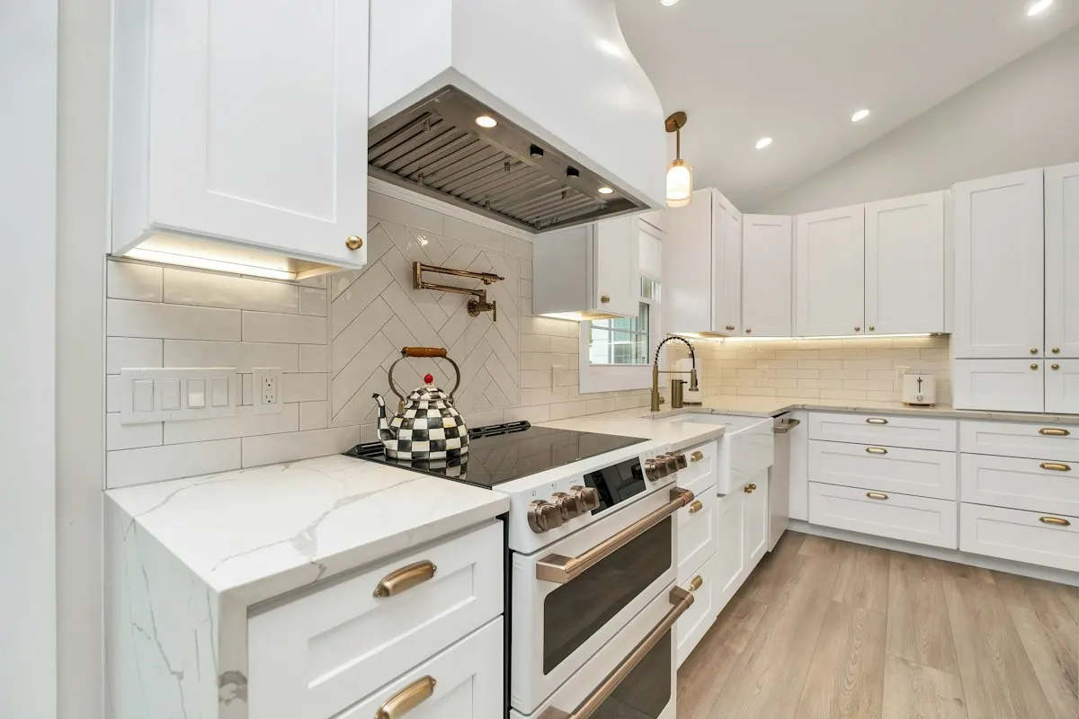 White shaker cabinets with under-cabinet lighting, a subway tile backsplash and a range under a hood